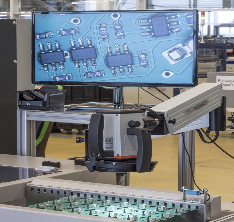 Qualitätsbewusste Produktion bei der INSTA Eine Maschine die eine Platine vergrößert auf einem Bildschirm ablichtet.